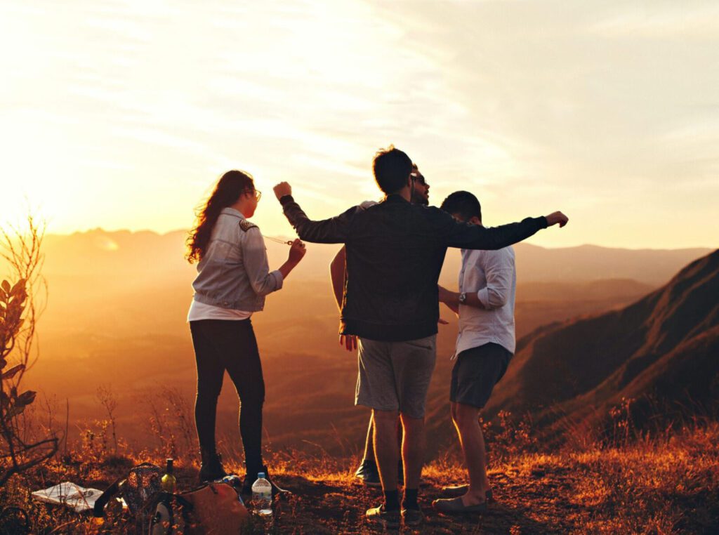 Three friends enjoying a sunset hike on a mountain.
